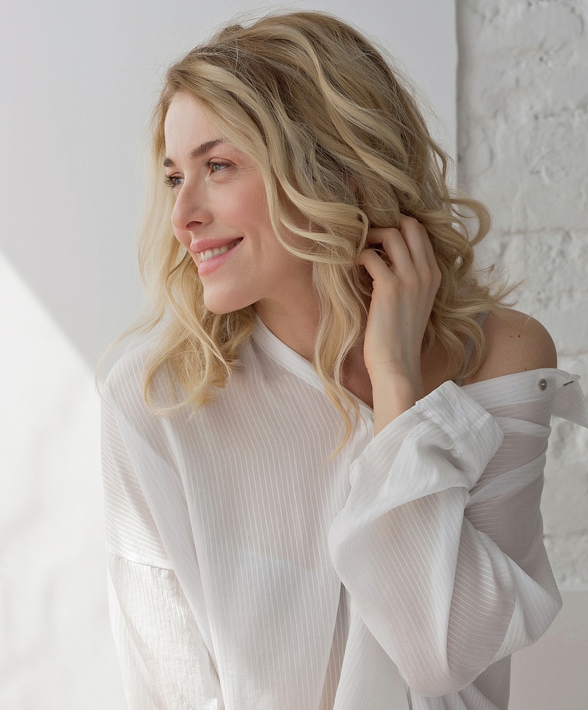 Wasilla Acne Treatment model with wavy hair in white shirt.